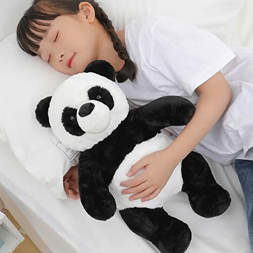 A child sleeping while hugging a panda teddy bear on a bed, showcasing its cuddly nature.