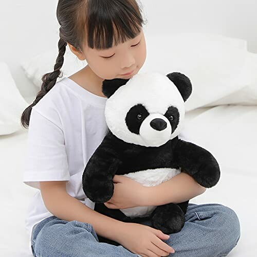 A child holding a panda plush toy while sitting, showcasing its cuddly nature.