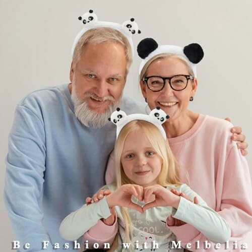 Smiling family wearing panda headbands, making heart shape with hands.