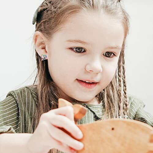 Young girl with braided hair playing with a wooden toy