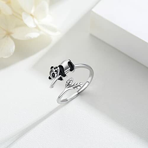 Panda ring on white surface with flower.