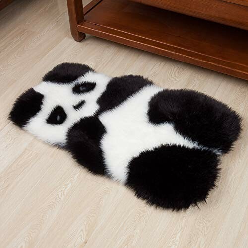 Panda-shaped fluffy rug on wooden floor.