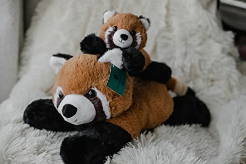 Two red panda stuffed toys on a fluffy surface